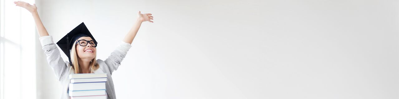 Jubelnde Frau mit Absolventenhut, vor ihr liegen gestapelte Bücher