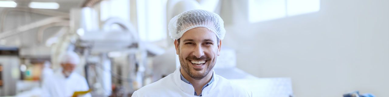 Mann mit Schutzhaube in Produktionshalle