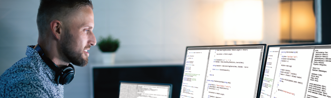 Junger Mann sitzt vor Bildschirmen