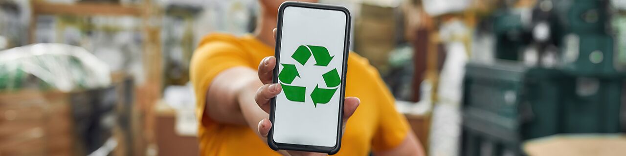 Frau hält Smartphone mit Recycling-Symbol nach vorne